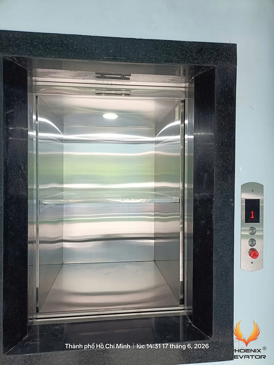Cabin inox của thang tải thực phẩm chia hai ngăn bằng khay cố định khi cửa nâng hạ mở