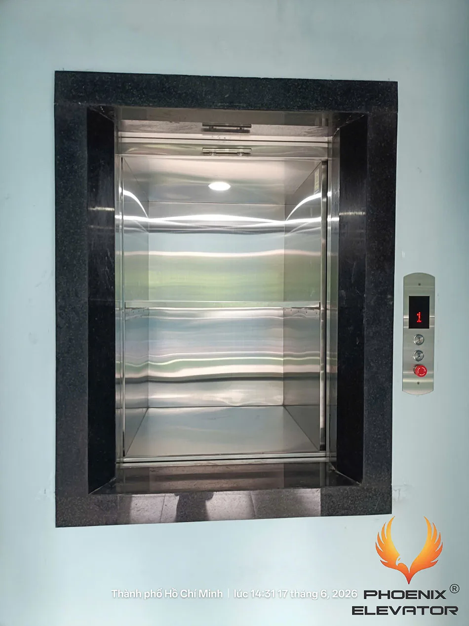 Cửa nâng hạ thang tải thực phẩm mở hoàn toàn để lộ ngưỡng cửa và khoang cabin inox