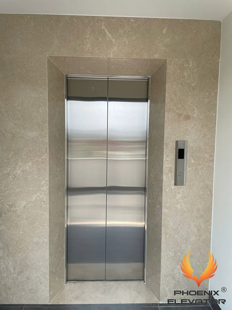 Cửa thang máy inox mở giữa lắp âm tường đá cho nhà cải tạo, kèm bảng gọi tầng