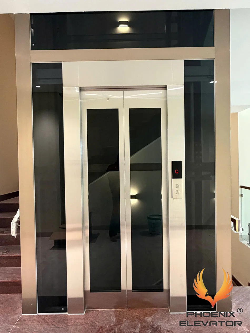 Thang máy khung nhôm màu bạc phối kính tối màu và inox đồng bộ tại sảnh thang