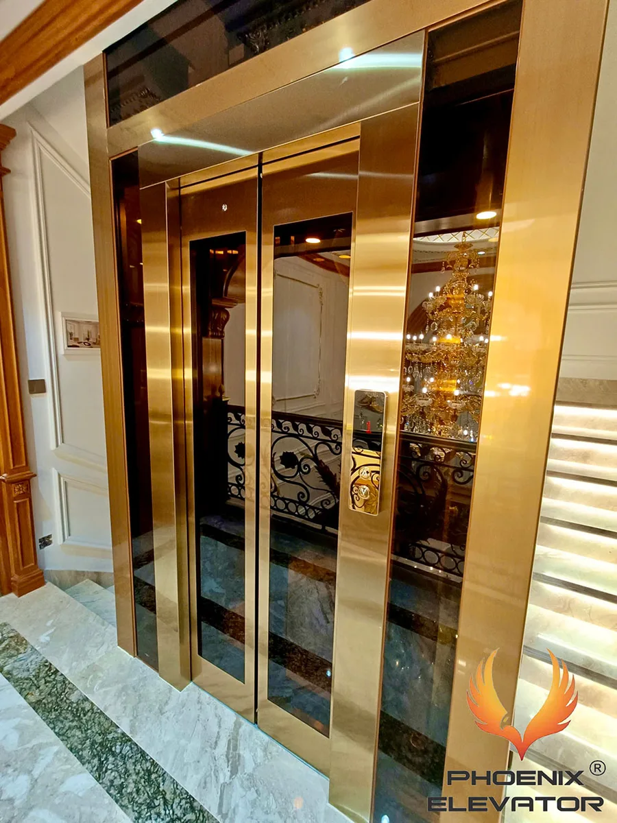 Thang máy khung vàng hoàn thiện trong nhà cải tạo, lắp liền cầu thang gỗ và nội thất sẵn có