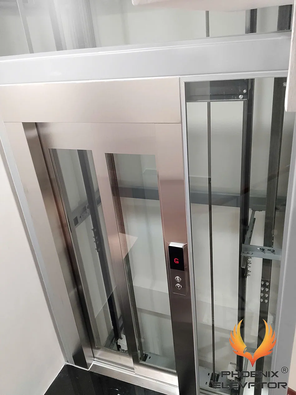 Thang máy QS07 mở cửa tại tầng G, nhìn thấy cabin inox kính và giếng thang bên cạnh