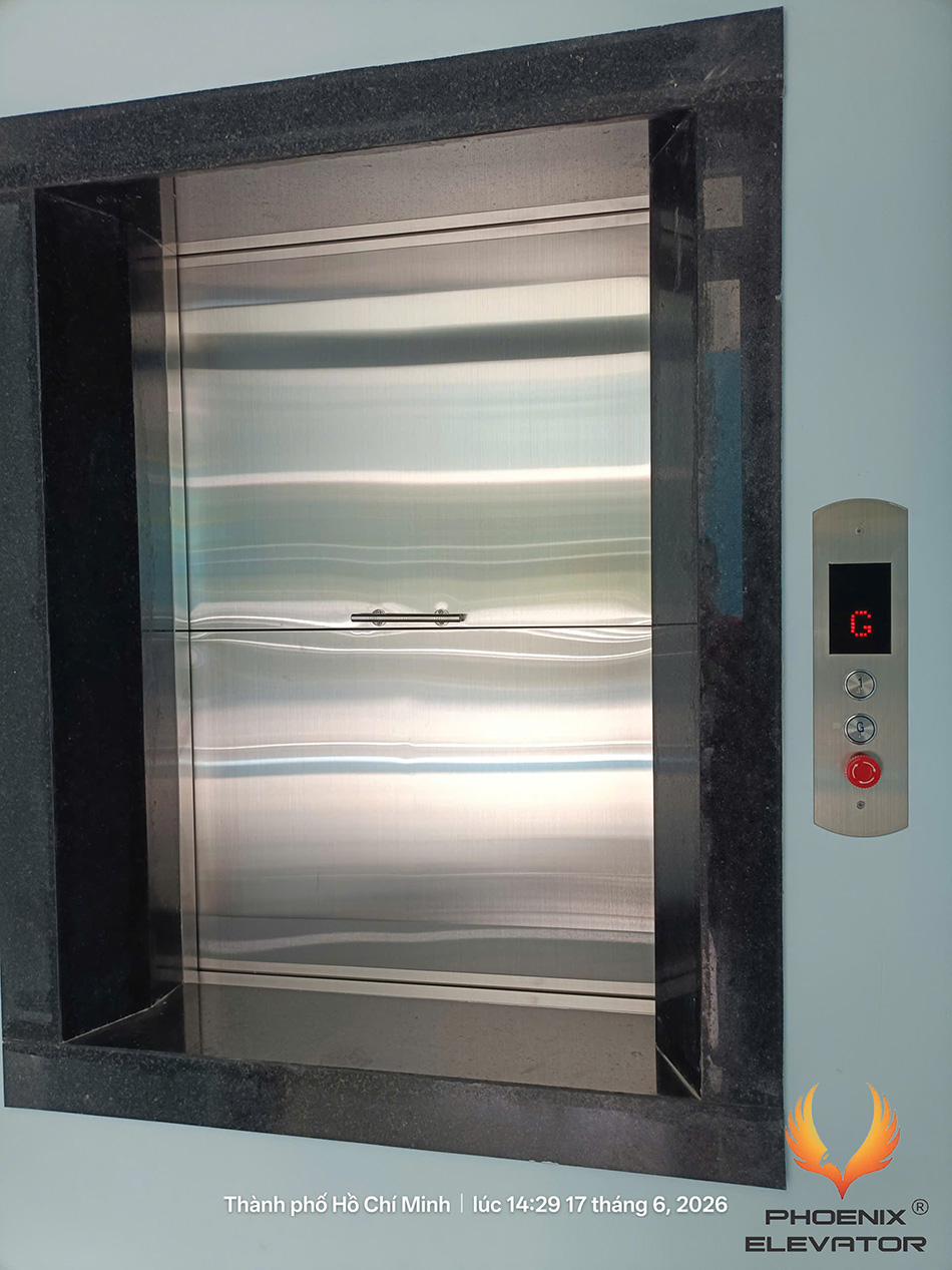 Cửa tầng inox của thang tải thực phẩm TP05 trong khung ốp đen tại công trình thực tế
