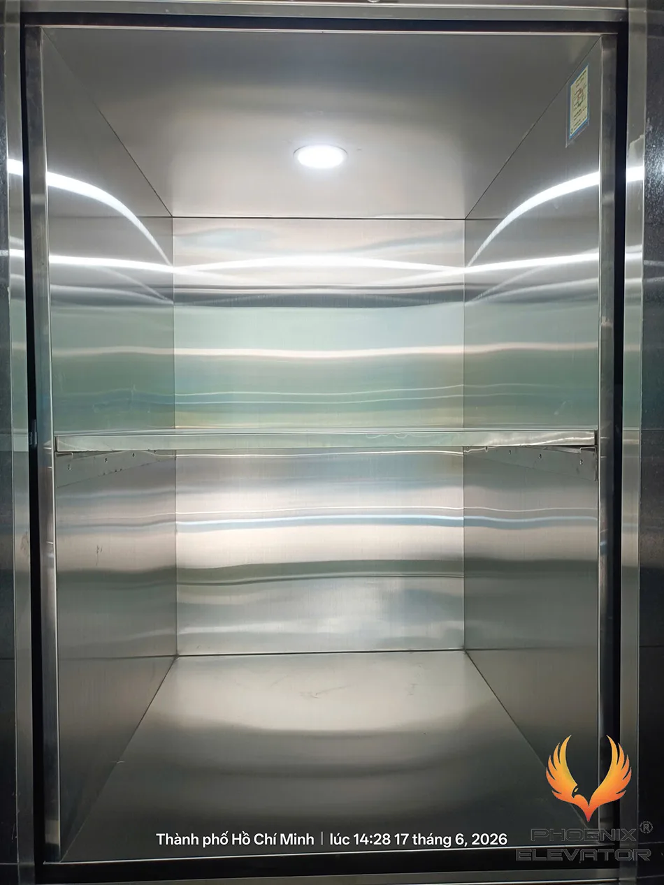 Lọt lòng cabin thang tải thực phẩm bằng inox 304 với một kệ ngang chia hai khoang xếp khay